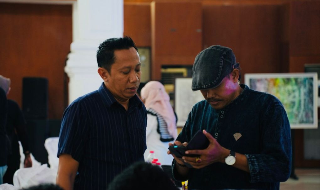 BERKEMAJUAN: Owner PR Cahaya Pro H. Fathor Rosi (kiri) saat berbincang dengan pelukis Boedi Madura di sela-sela Temu Wartawan dan Pengusaha oleh PWI Pamekasan. (Moh Miftahol Arifin/Kabar Madura)