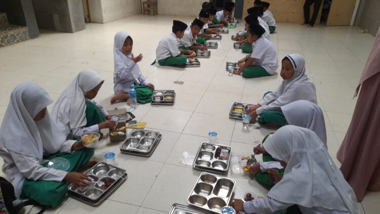 DAPAT ATENSI: Para siswa sedang menikmati menu MBG. (Moh. Razin/Kabar Madura)